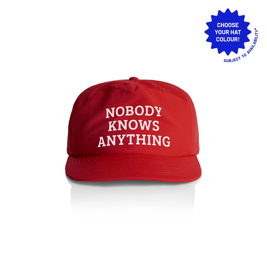 A red baseball cap with white text that reads 'Nobody Knows Anything'. the hat is made from recycled materials